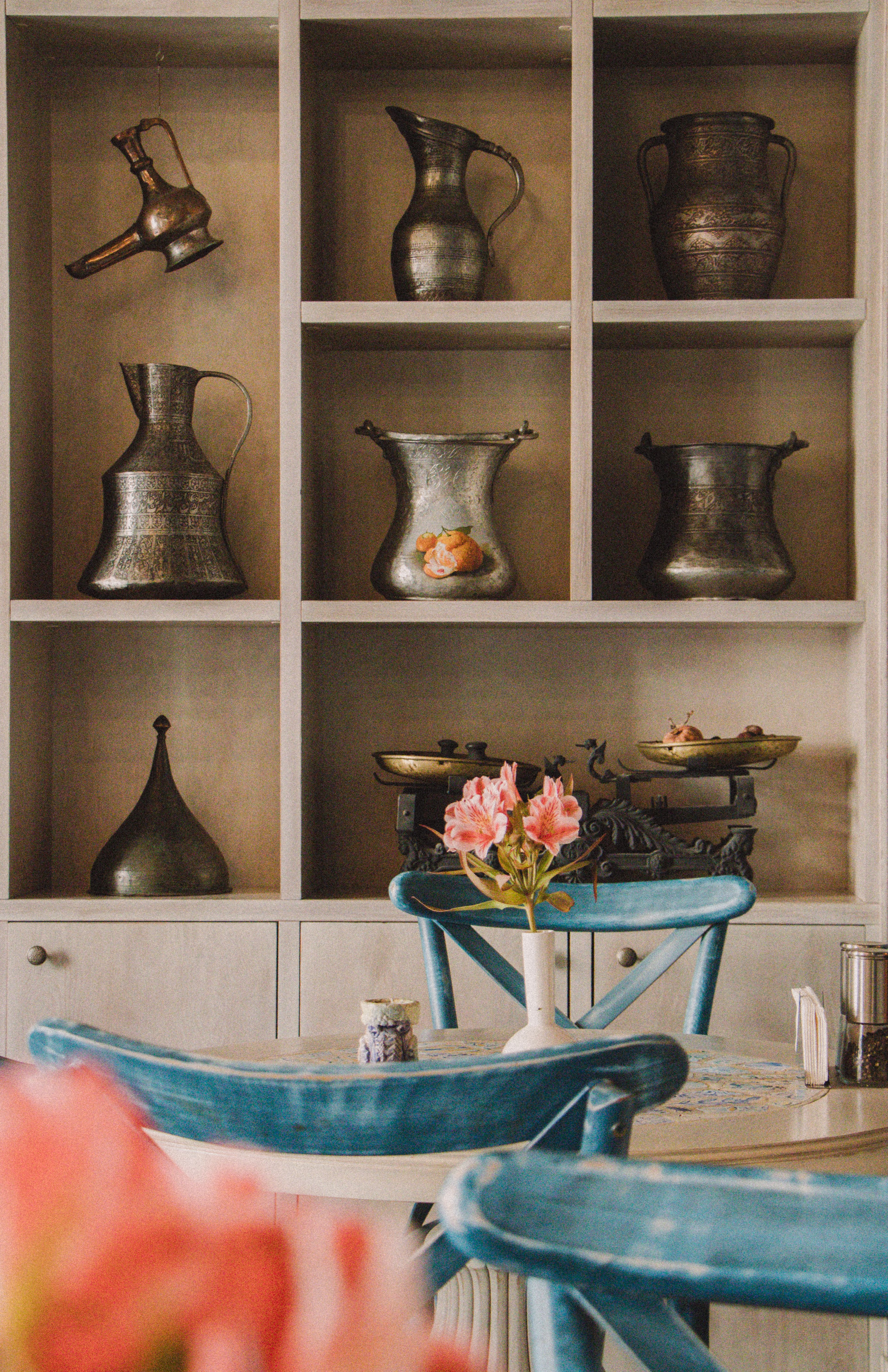 A charming vintage café interior featuring rustic metal pitchers and floral decor.