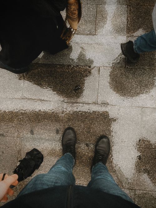 Free High angle view of urban street with wet pavement showcasing various footwear. Stock Photo