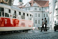 红白电车行驶在鹅卵石街道上，与欧洲城市场景中的人们一起，传达出城市交通的氛围