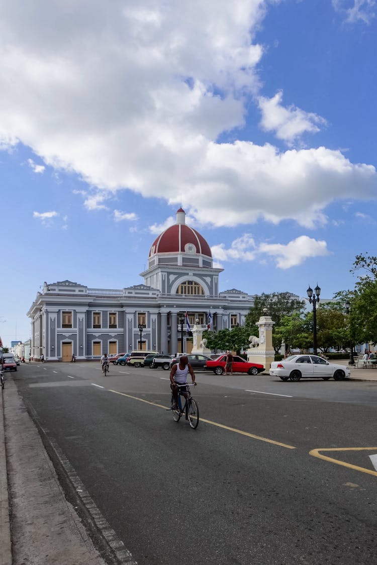 People Riding Bikes On Road Near Old Historic Building