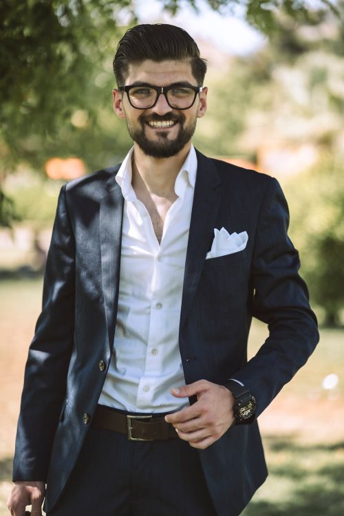 Free Smiling man in a stylish suit posing outdoors in summer sunlight. Stock Photo
