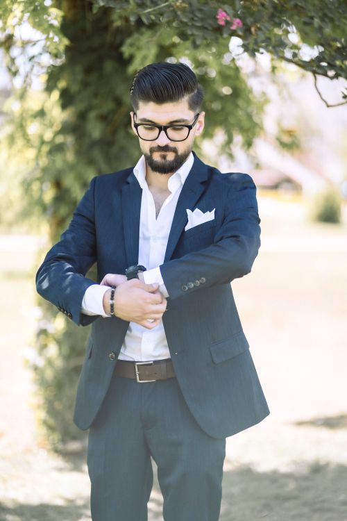 Free Elegant man in glasses adjusts his suit outdoors on a sunny day in Gaziantep, Turkey. Stock Photo