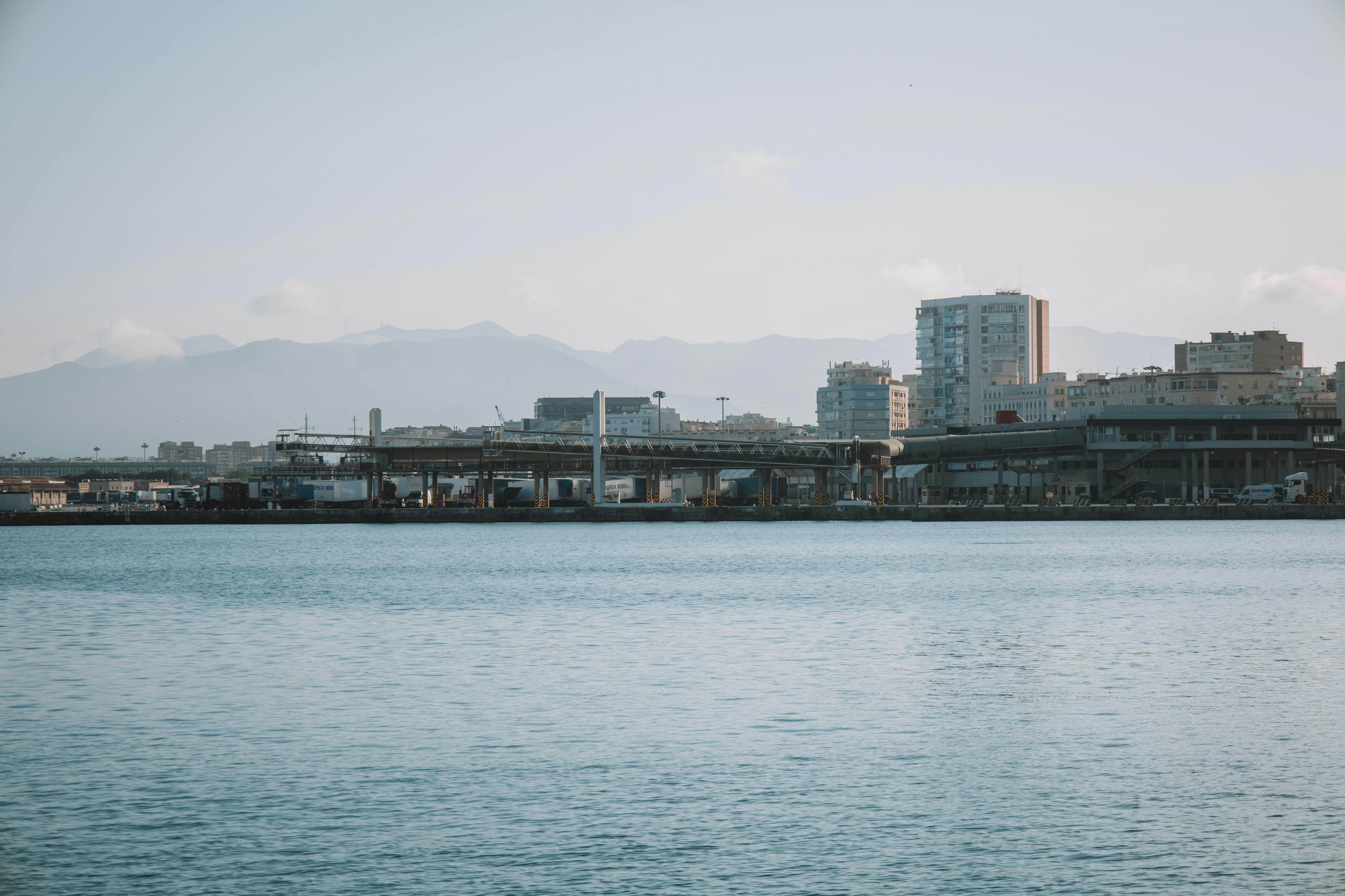 Scenic view of Málaga harbor with urban skyline and mountains in the background.