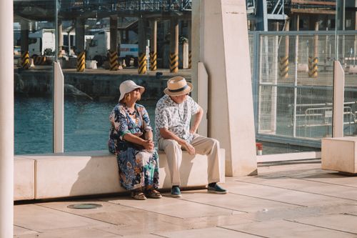 Free Elderly couple sitting by the waterfront in Málaga, enjoying a sunny summer day. Stock Photo