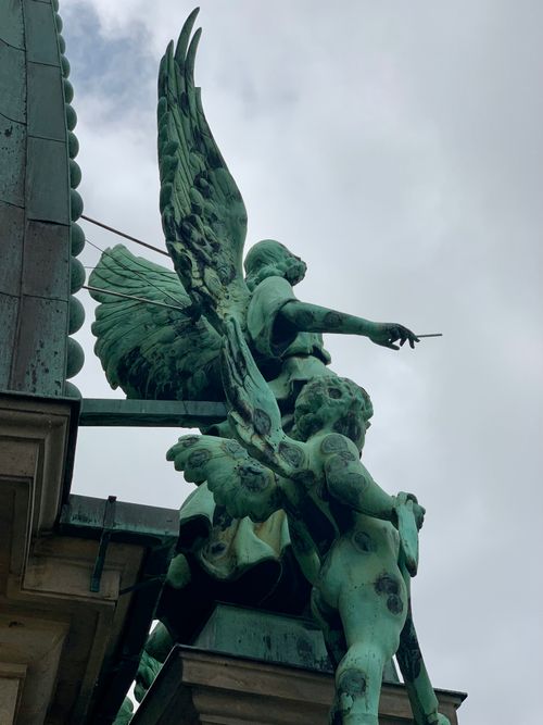Free Low angle view of an ornate angel sculpture with outstretched wings set against an overcast sky. Stock Photo