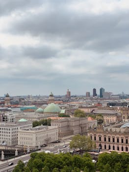 A stunning aerial view of Berlin showcasing historic architecture under a cloudy sky.