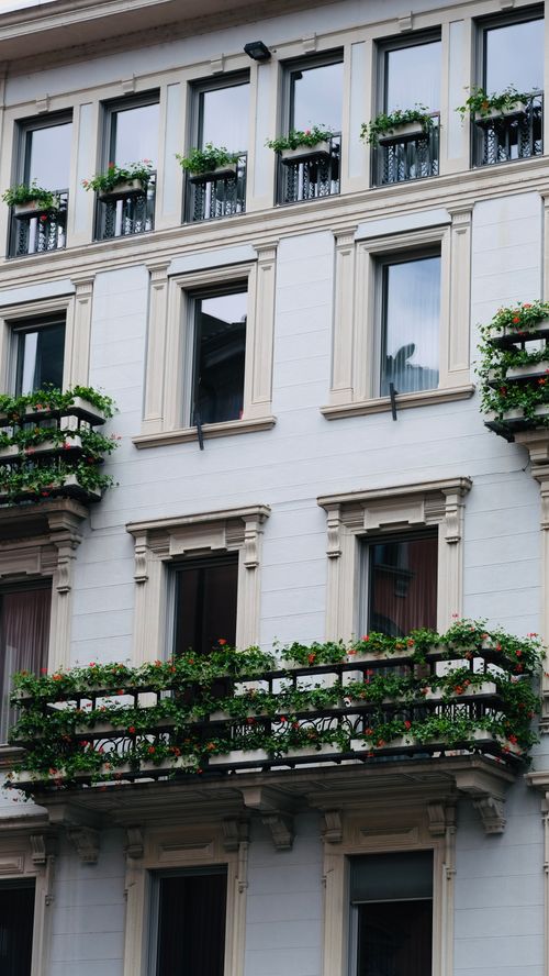 Free Elegant building exterior with lush green balconies adorned with plants. Stock Photo