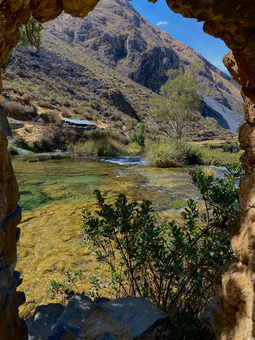 Free A beautiful view through a natural arch revealing a tranquil river and mountainous landscape. Stock Photo