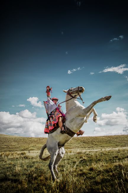 A vibrant scene of a rider in traditional clothing on a rearing white horse, set in Espinar, Peru.