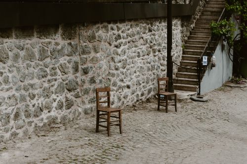Free Wooden chairs by a rustic stone wall on a cobblestone street in Istanbul. Stock Photo