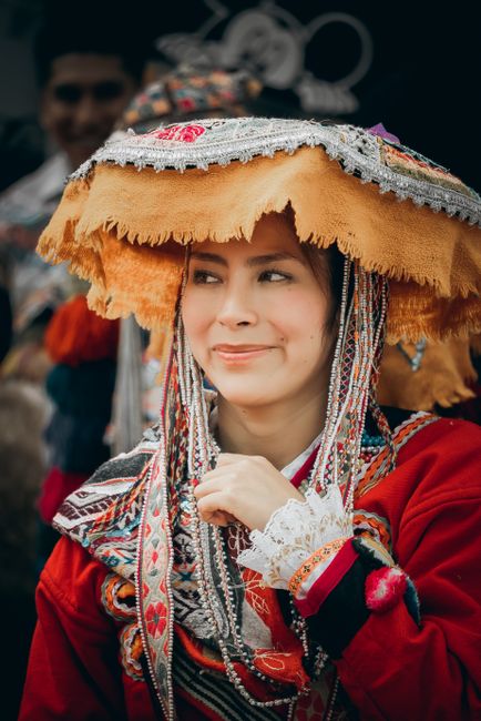 A woman in vibrant Andean attire smiles, showcasing Peruvian culture and tradition.