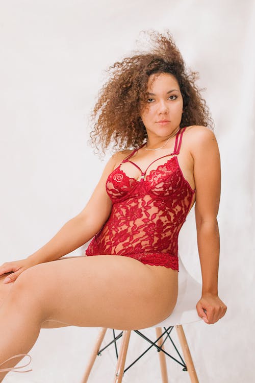 Woman in Red Bodysuit Sits in Chair
