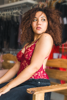 Portrait of a stylish woman in red lingerie sitting on a wooden bench.