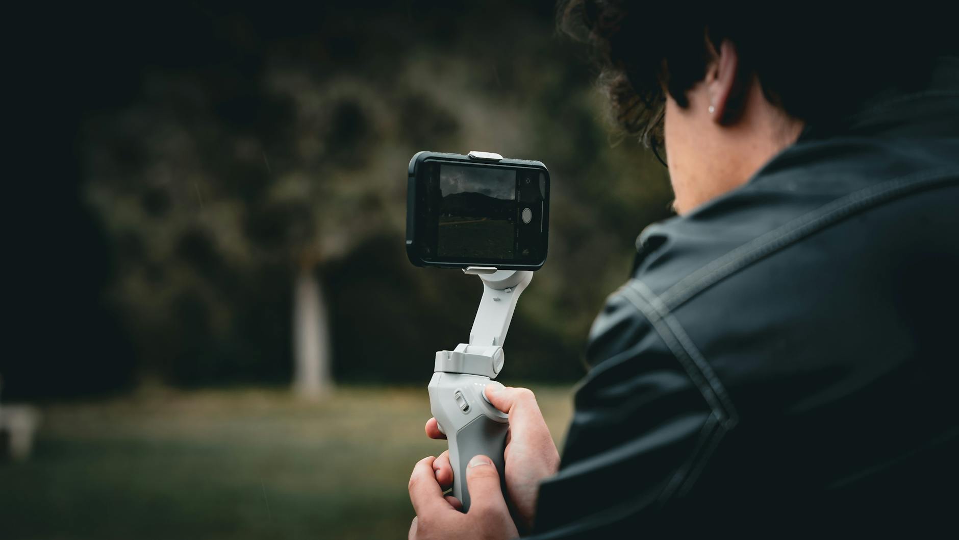 A man uses a smartphone gimbal outdoors, capturing stable video footage.