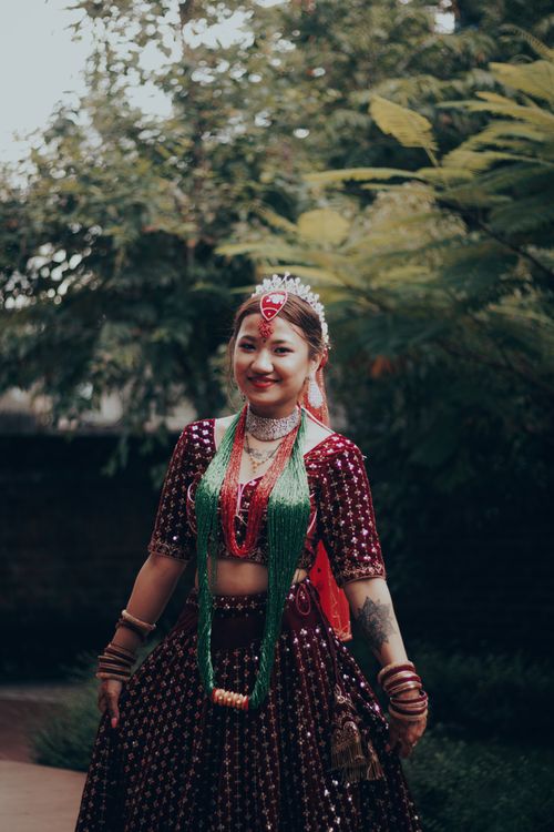 Free Smiling woman in traditional attire posed in a lush garden, celebrating cultural heritage. Stock Photo