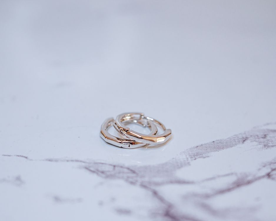 A pair of gold rings sitting on top of a marble table · Free Stock Photo