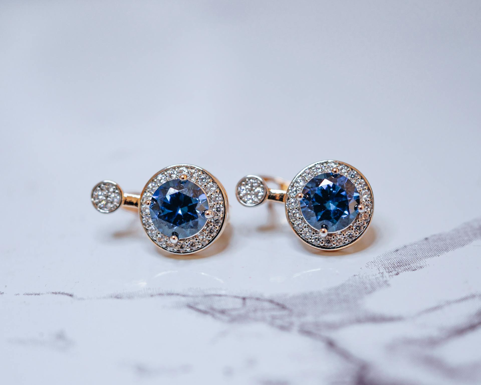 Close-up of luxurious sapphire and diamond earrings displayed elegantly on a soft background.