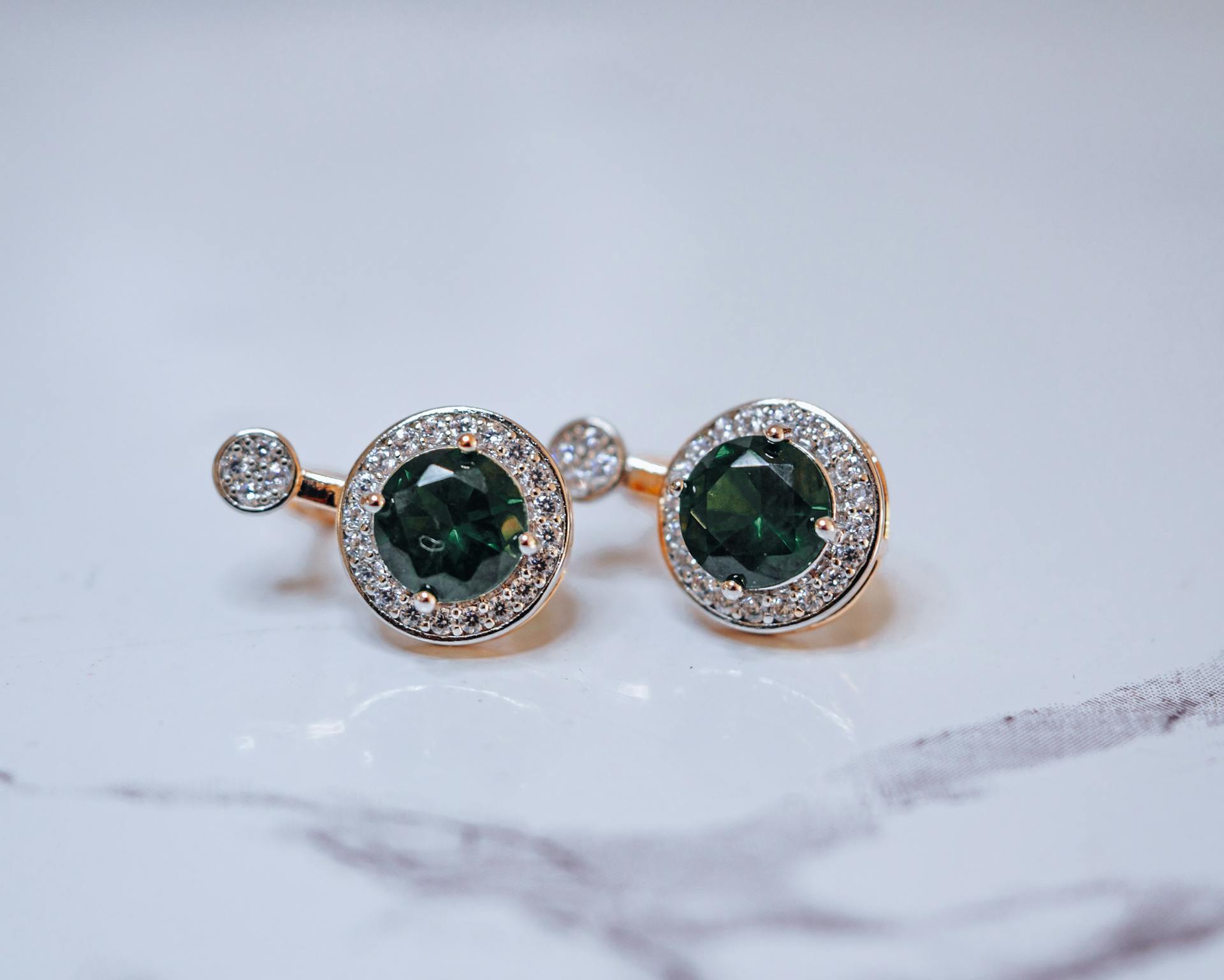 Close-up of luxurious green sapphire and diamond earrings, showcasing elegance and style.