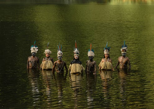Tribal members in traditional attire stand in water, Tingo María, Peru.
