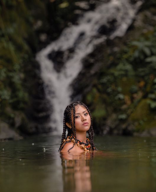 A woman with plaited hair enjoying tranquility in a natural pool near a waterfall in Tingo María, Peru.