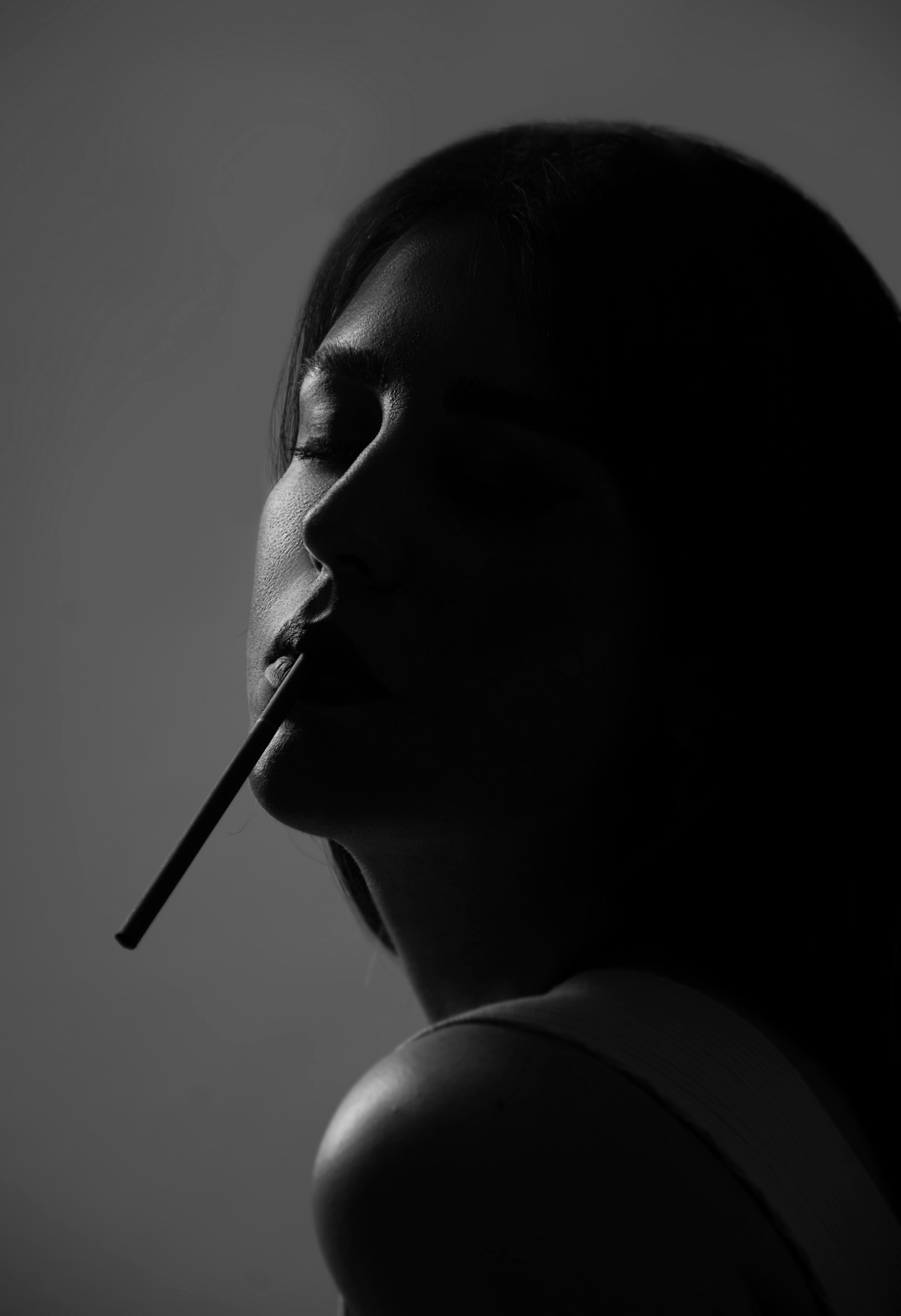 a cigarette pressed between her lips Woman with Cigarette in Mouth · Free Stock Photo
