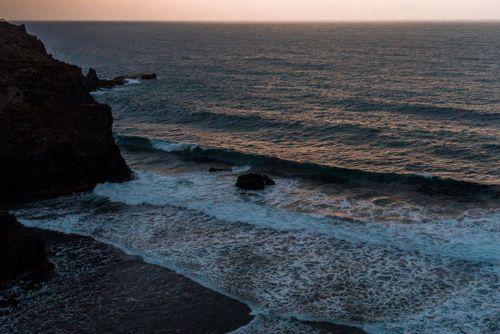 Free Calm ocean waves hitting rocks by the shore at sunset, creating a serene coastal view. Stock Photo