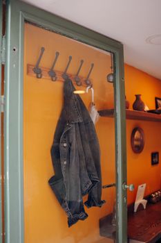 Denim jacket hanging on hooks in a cozy home interior with warm lighting.