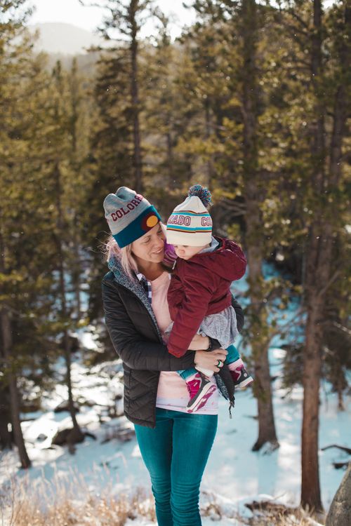 Free A mother and child smiling while enjoying a winter day in a snowy forest. Stock Photo