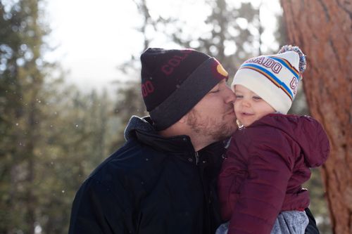 Free A father kisses his toddler on a sunny winter day in Colorado, with snowflakes gently falling. Stock Photo