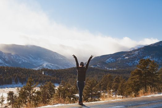 A person joyfully raises arms in a stunning winter mountain landscape.