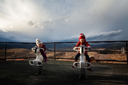 Free Two young children having fun on playground rides outdoors against a scenic backdrop. Stock Photo