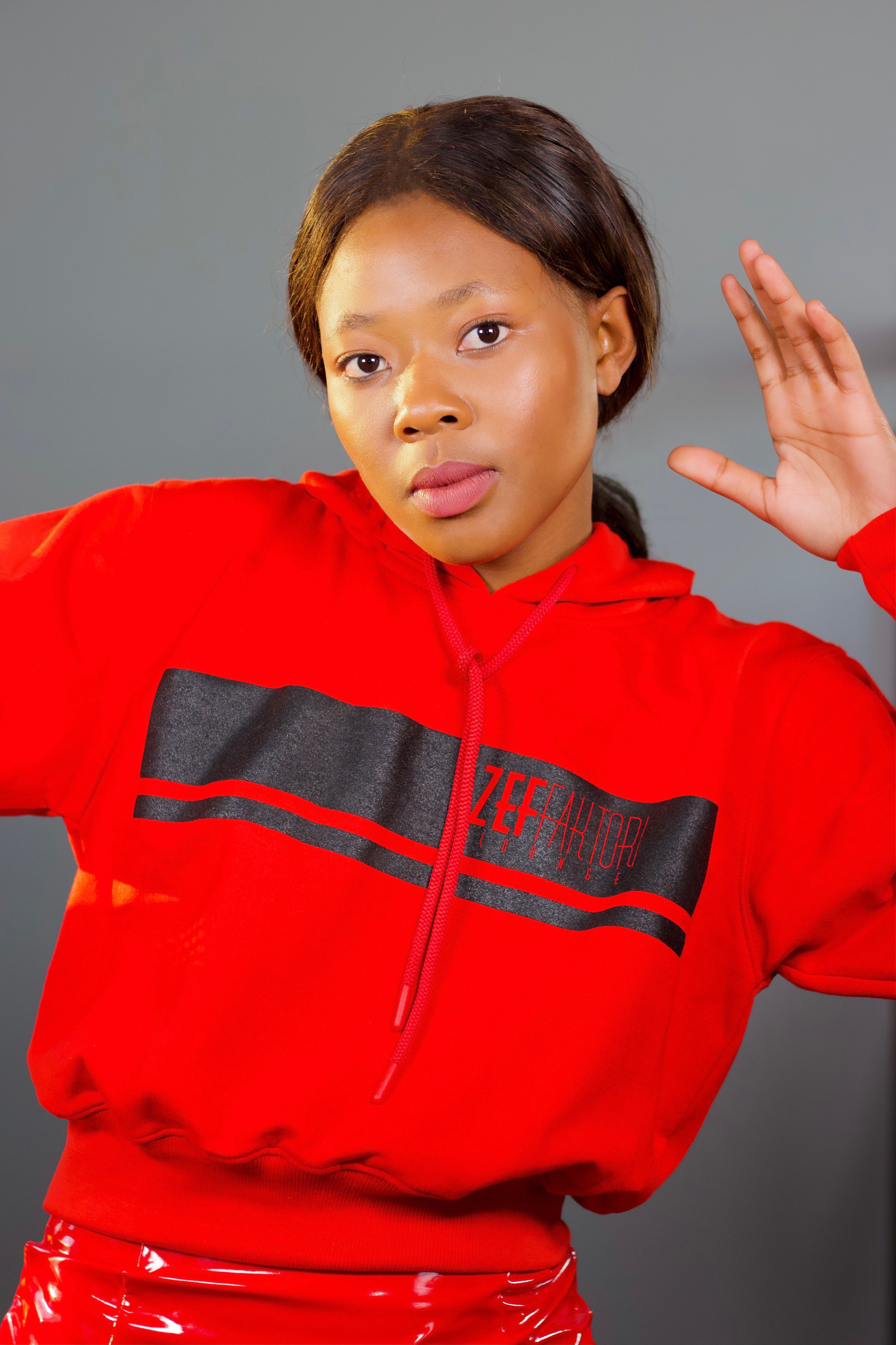 Stylish portrait of a woman in a red hoodie with a gray background.
