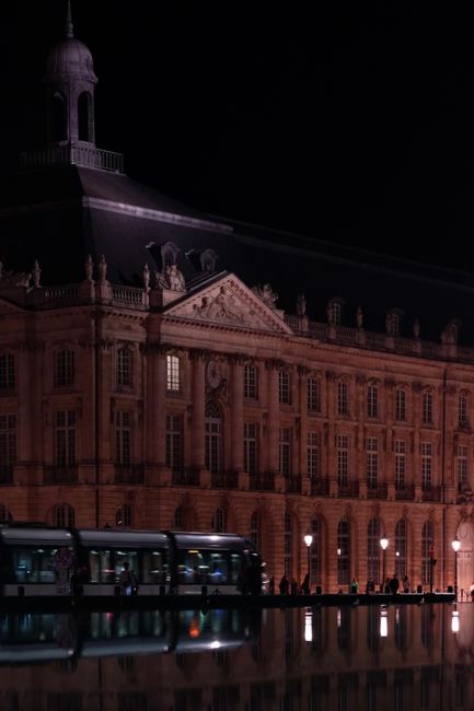 Fotomural Plaza de la Bolsa en Burdeos iluminada por la noche, reflejándose en el agua.