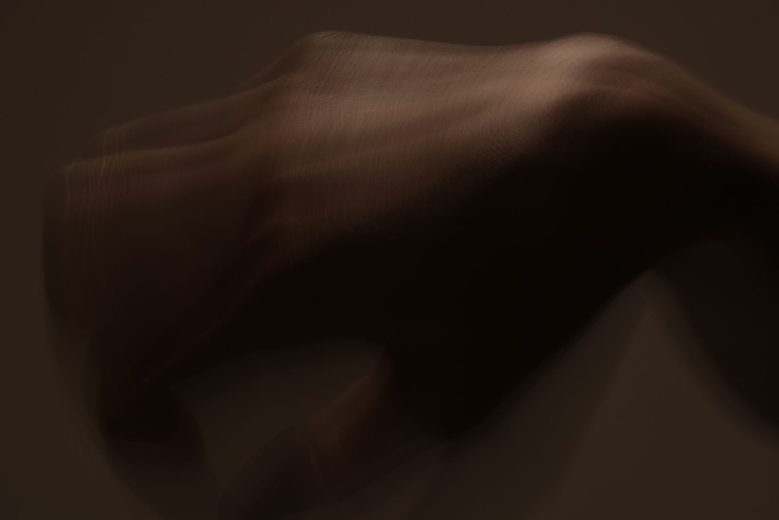 Person gently holding their thumb and wrist while sitting in bright natural light
