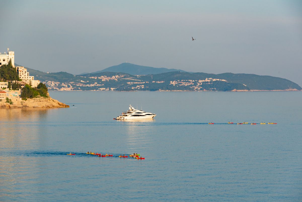 Kayakers and yacht by the Dubrovnik coastline on a summer day