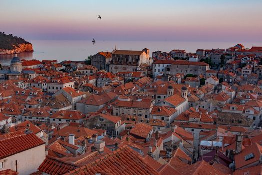 A breathtaking aerial view of Dubrovnik's historic rooftops at sunset, overlooking the Adriatic Sea.