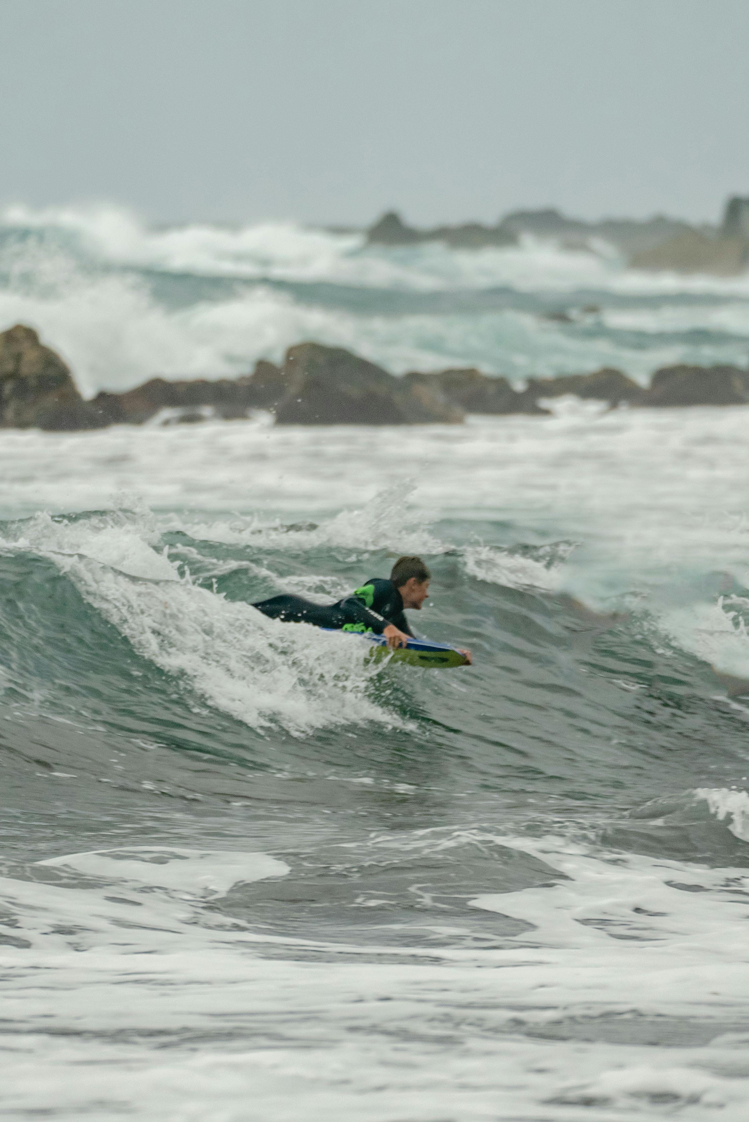 A man in a wetsuit surfing in dynamic ocean waves on a cloudy day.