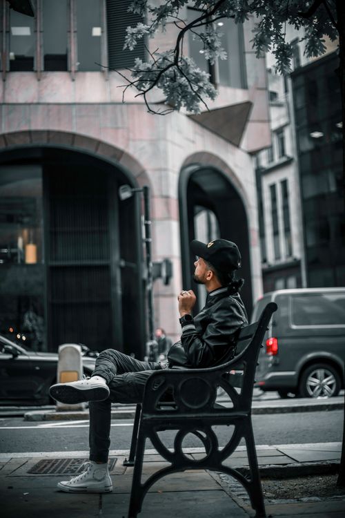 Free A man in casual wear sits on a bench, embodying urban street style. Stock Photo