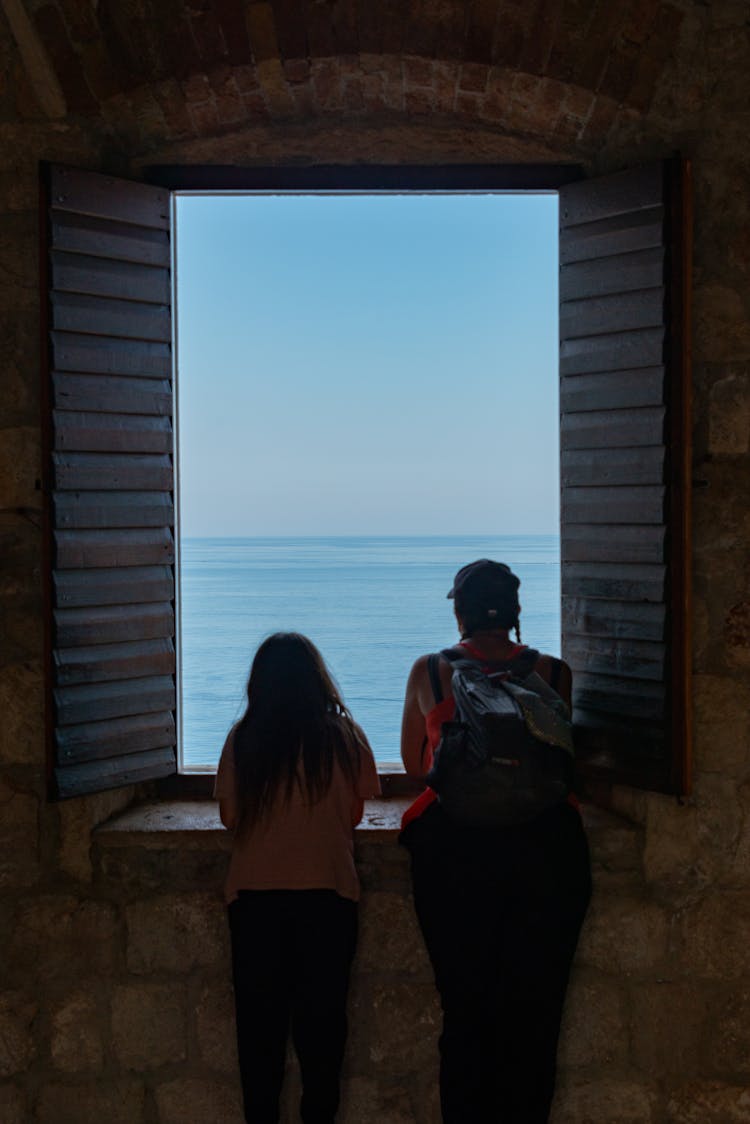 Woman And Child Looking Out Of Window On Sea