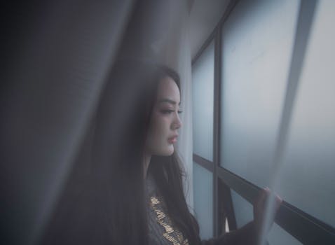 年轻女子若有所思地凝视着雾蒙蒙的窗外，捕捉到了一个内省的时刻