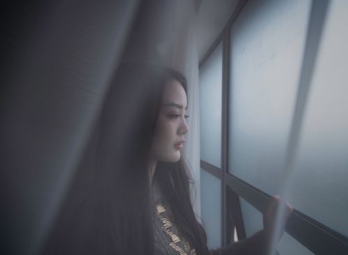 Free Young woman gazing thoughtfully through a foggy window, capturing a moment of introspection. Stock Photo