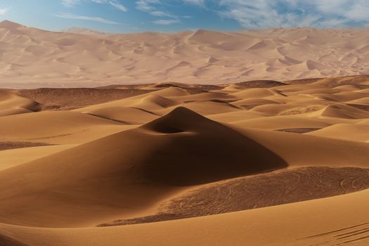 Stunning view of endless sand dunes under a bright blue sky in a pristine desert setting.