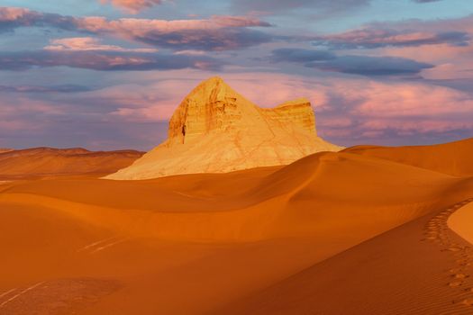 Breathtaking view of a desert landscape with a striking rock formation under a vibrant sunset.