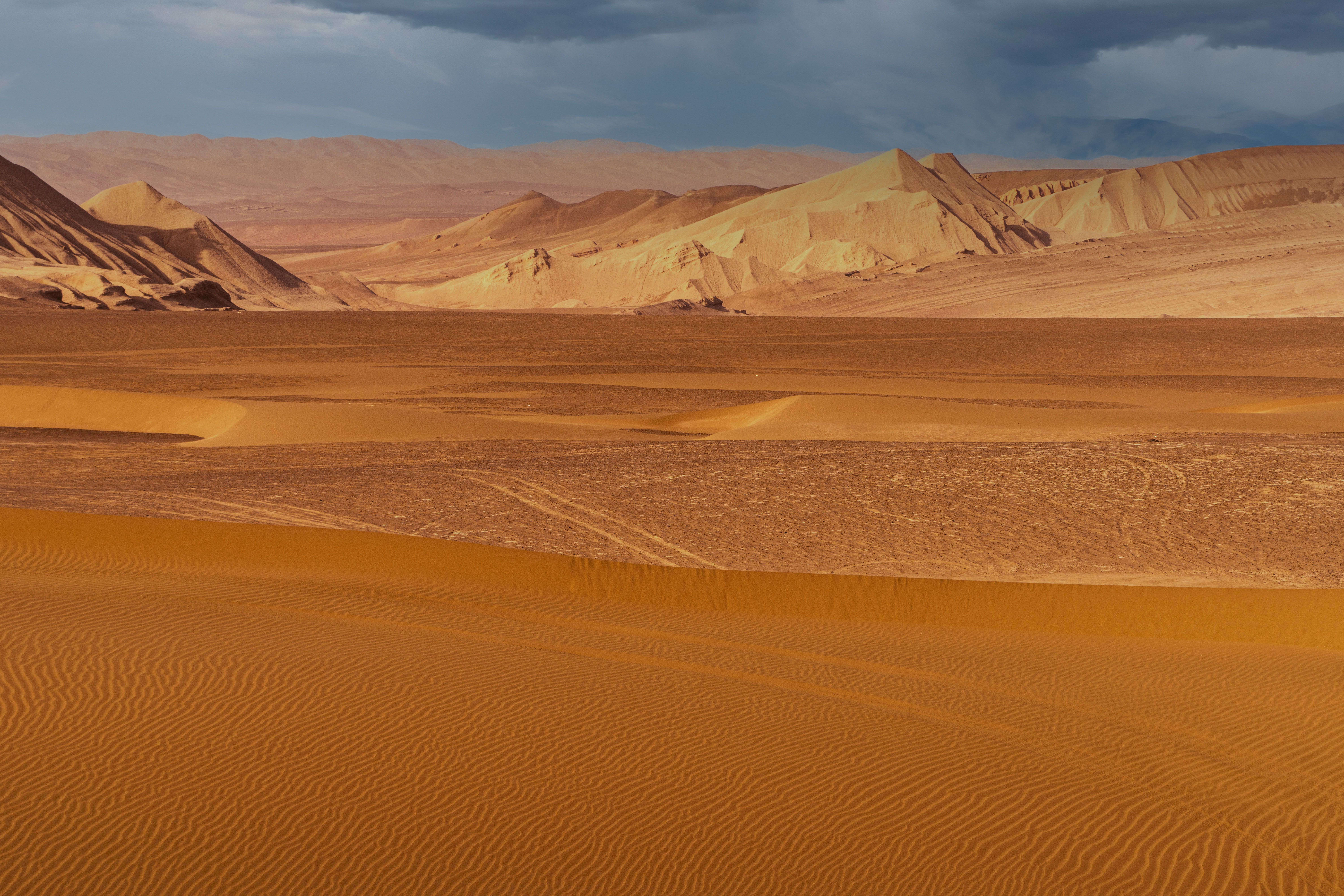 Stunning aerial shot of two cars making tracks on vibrant red sand dunes in a desert landscape.