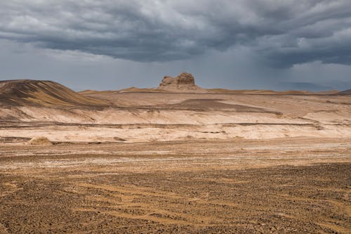 Desert Landscape and a Rock Formation under an Overcast Sky 