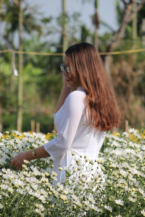 Vrouw In Witte Jurk Die Zich Op Bloemgebied Bevindt