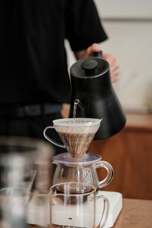 Close-up of a Person Pouring Hot Water to a Coffee Pot with a Filter