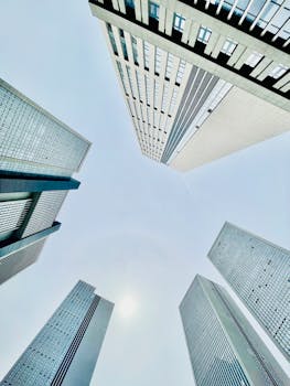 Low angle shot of modern skyscrapers forming a geometric pattern against a clear blue sky.