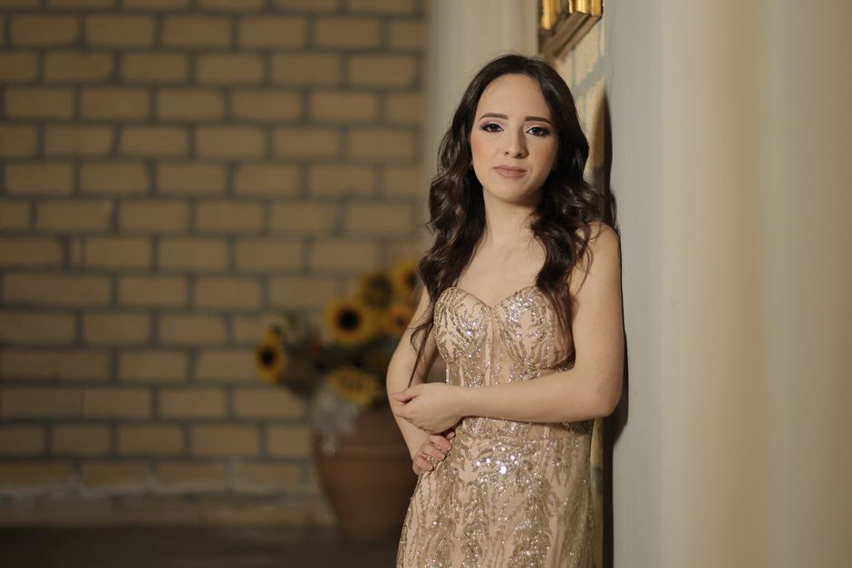 A young woman elegantly posing in a sequin dress indoors, with a stylish and glamorous look.