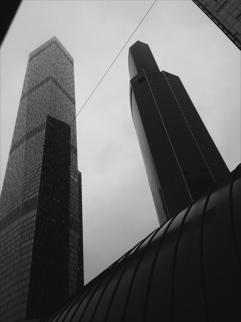 Black and white photo of towering urban skyscrapers from a low angle perspective.